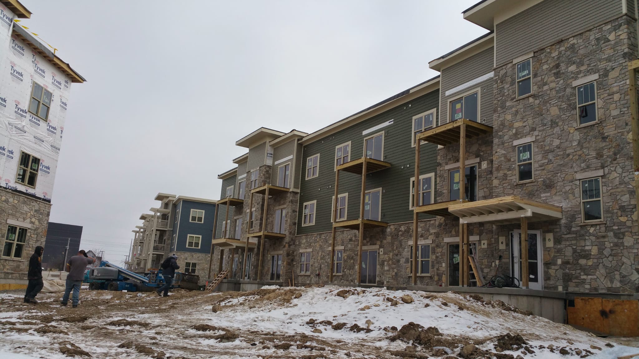 Active winter jobsite with workers installing siding