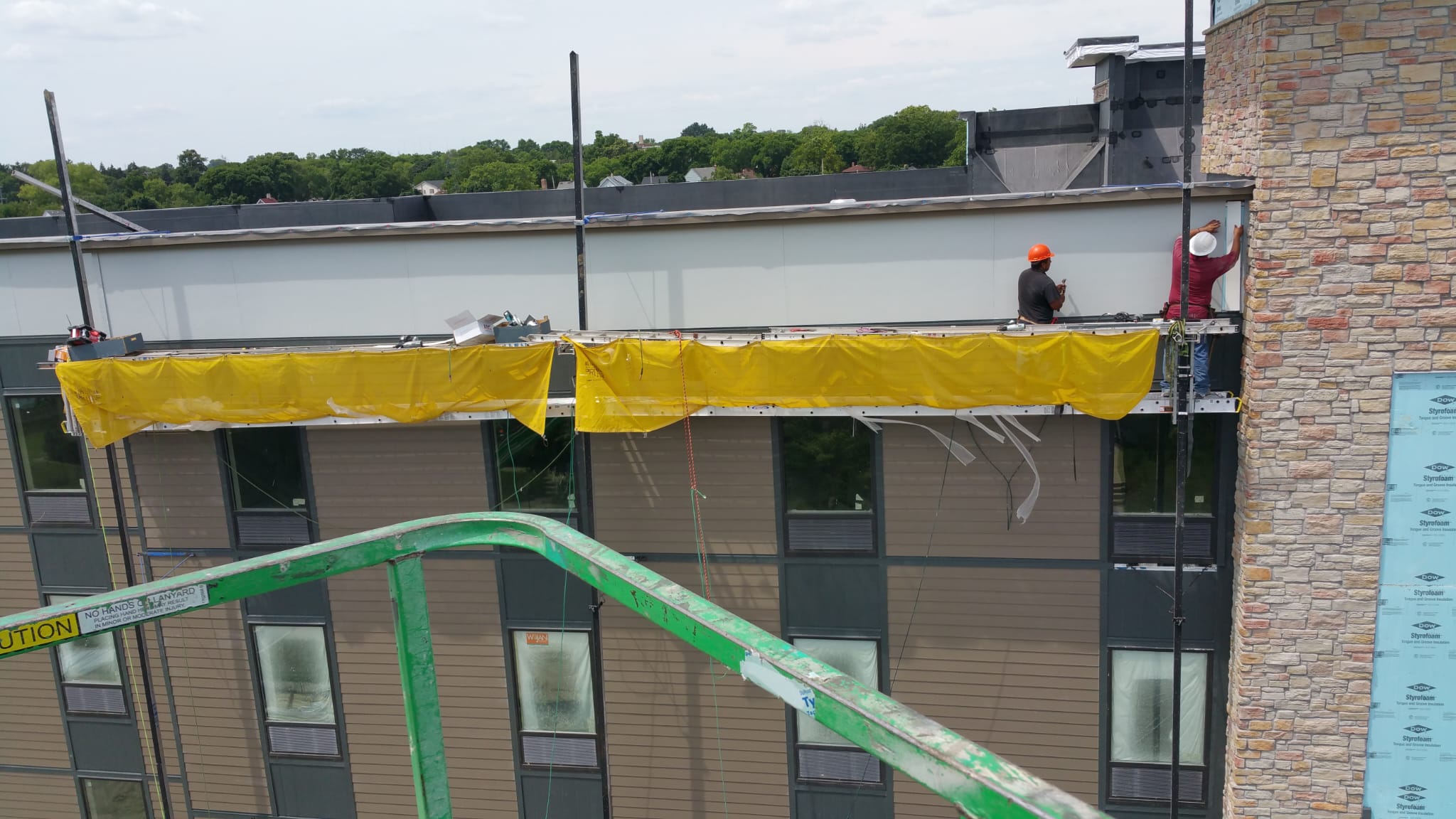 Workers on lift installing siding on commercial building